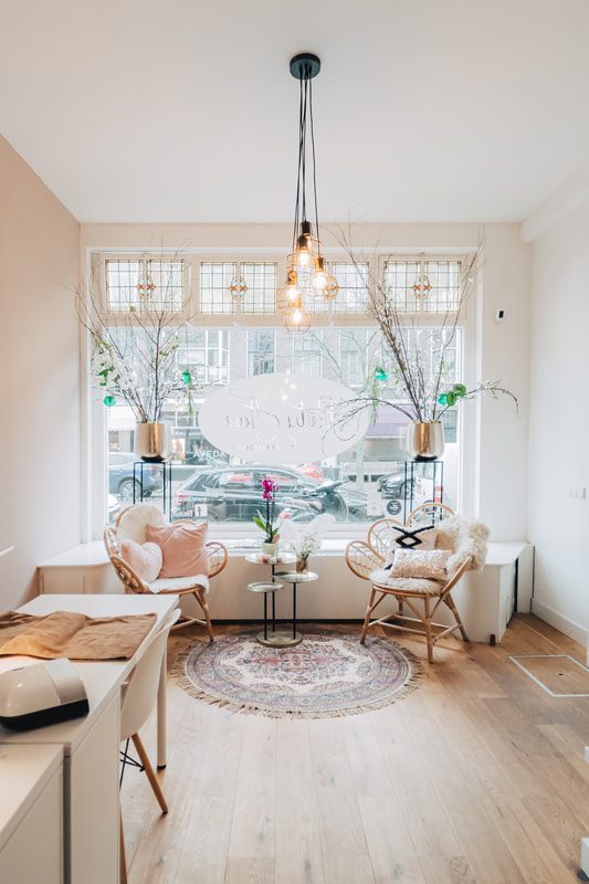 Lichte wachtruimte bij het raam van Pretty Face, met rotan stoelen